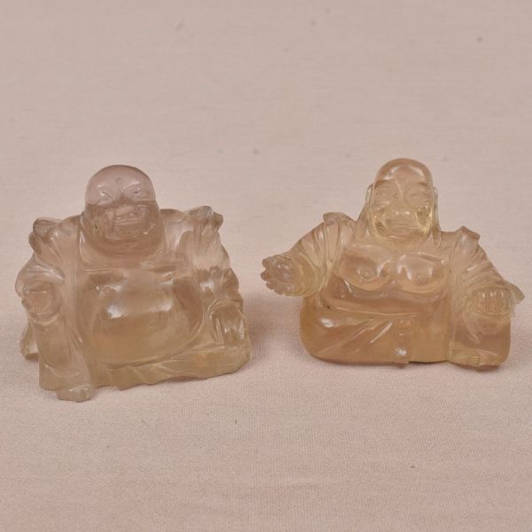Duas esculturas chinesas em cristal de rocha representando Budas em tom ambar. Alt. 5 cm. Uma peça com quebradinho no ombro.