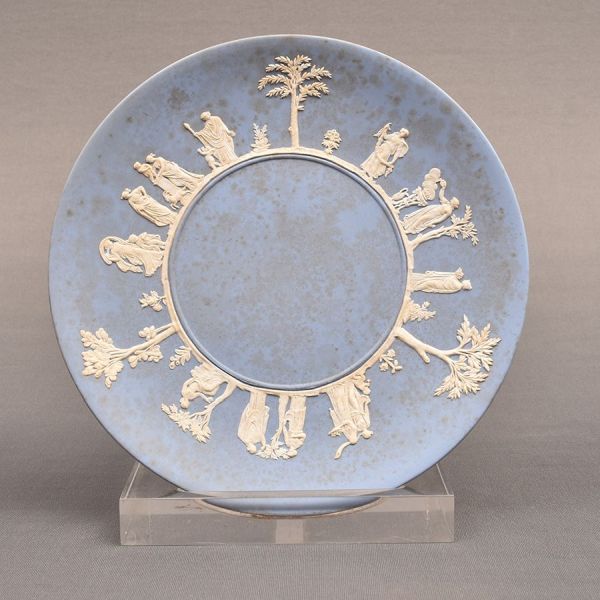 Wedgwood. Prato inglês Jasperware na cor azul não esmaltado, decoração em relevo branco com figuras gregas. Diam. 24 cm.