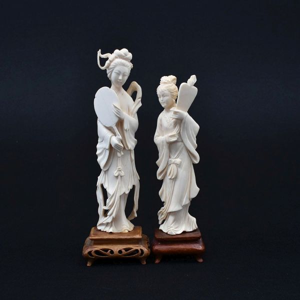 Par de estatuetas de marfim chinês cerca de 1940 representado figuras de damas. Base de madeira. Alt. total 21 e 18 cm.