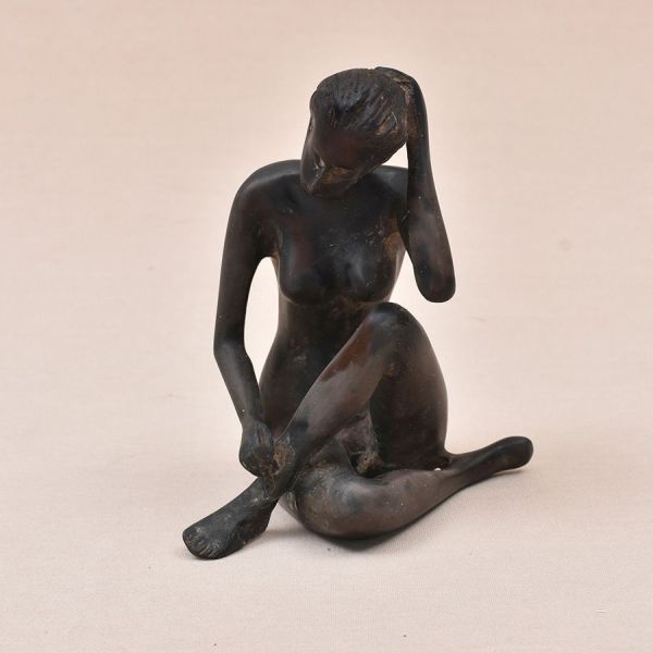 Escultura chinesa em gipsita patinado representando figura feminina sentada. Um pé representando restauro. Alt. 15 cm.
