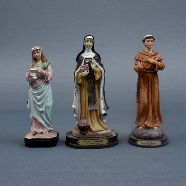 Três santos sendo 2 em resina e um em gipsita. Frei galvão, Santa Edwiges e Santa Luzia. Alt. 22, 22 e 20 cm.