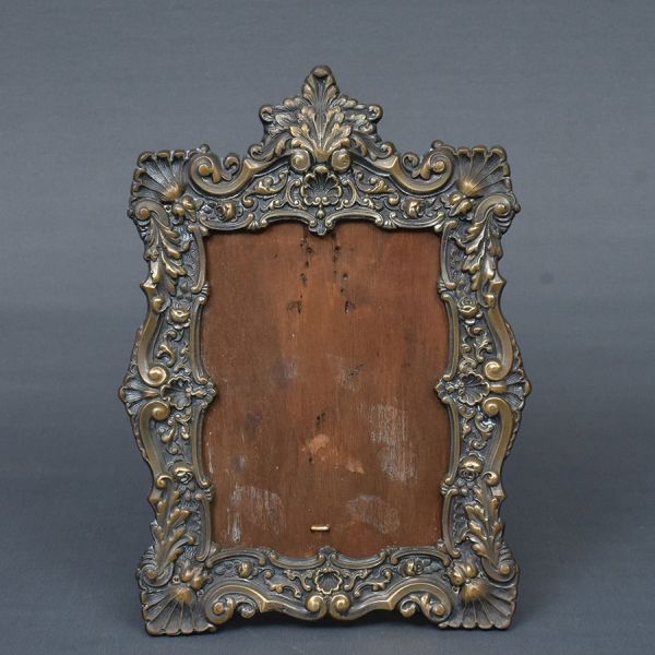 Porta retrato de bronze e madeira cinzelado com volutas e acantos. Med. 34 x 23 cm. Med. interna 23 X 17 cm