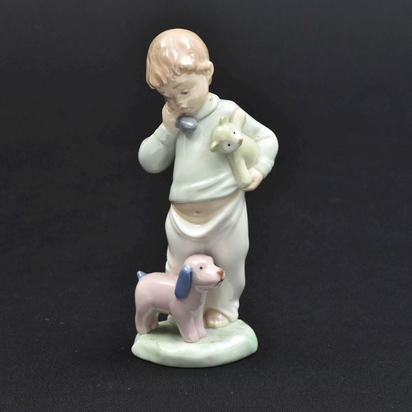 Estatueta de porcelana espanhola NÃO-Lladro representando figura de menino com seus bichinhos. Alt. 18 cm.