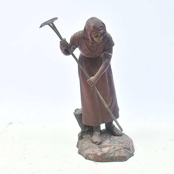 Grande escultura europeia em petit bronze representando figura de camponesa arando a terra. Alt. 60 cm.