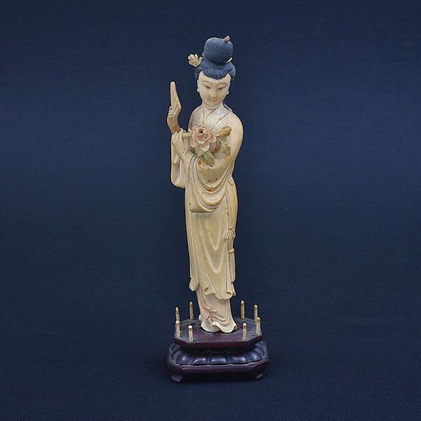 Estatueta de marfim chinês representando dama com leque e flores. Alt. 26 cm. Base de madeira 30 cm.