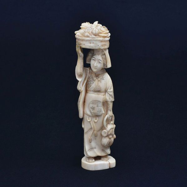Estatueta de marfim japonês cerca de 1940 representando gueixa com cesto de flores. Alt. 21 cm.