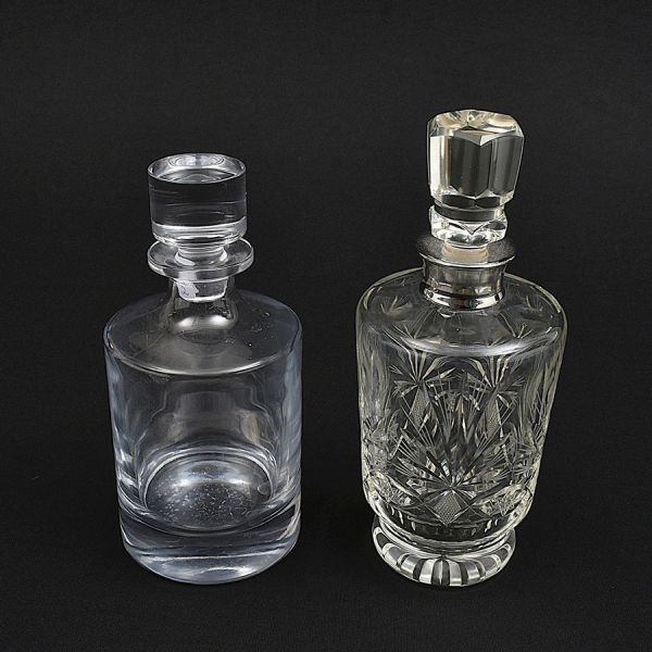 Duas garrafas de cristal europeu redondas, sendo uma lisa e uma lapidada. Alt. 27 e 24 cm.