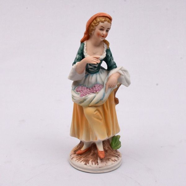 Estatueta europeia em biscuit policromado representando camponesa. Alt. 19 cm.