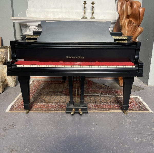 Piano meia cauda da marca Rud Ibach Sohn, apresentando acabamento clássico em preto brilhante. Altur