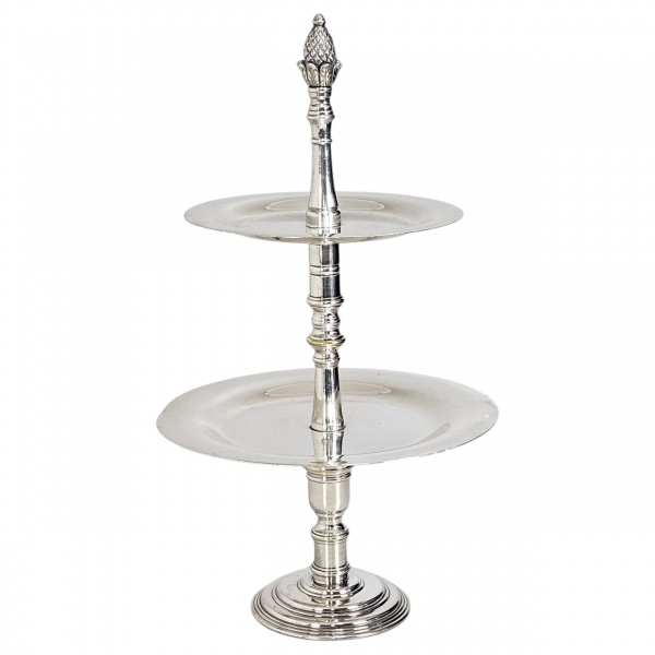 Doceiro de dois andares em metal prateado, composto por base circular escalonada, haste central torneada com anéis decorativos e duas bandejas circulares de tamanhos decrescentes (a inferior maior e a