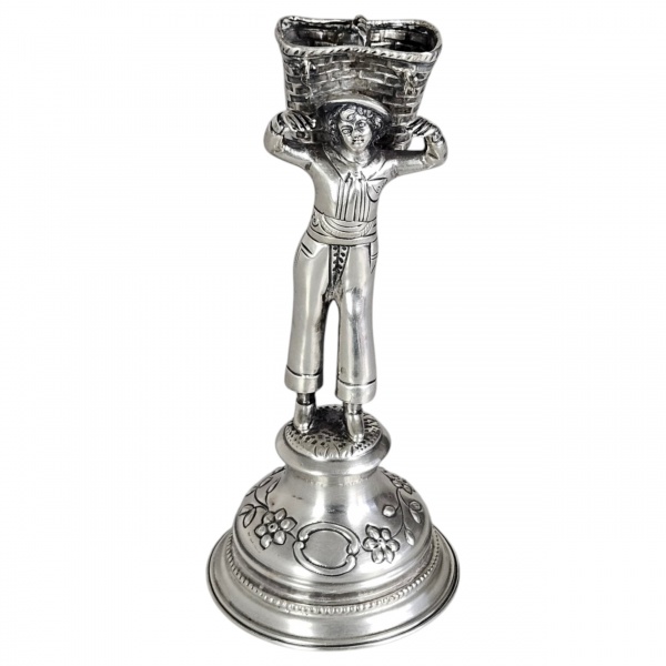 Paliteiro de prata portuguesa. Apresenta base circular escalonada que apoia figura de camponês carregando cesto. 18 cm de altura, Peso aproximado 170g.