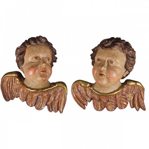 Par de cabeças de querubins alados (arte sacra) estilo Barroco. Escuulpidas em madeira com acabamento em policromia, apresenta asas decoradas com pátina ou folha de ouro e rostos expressivos com bobec