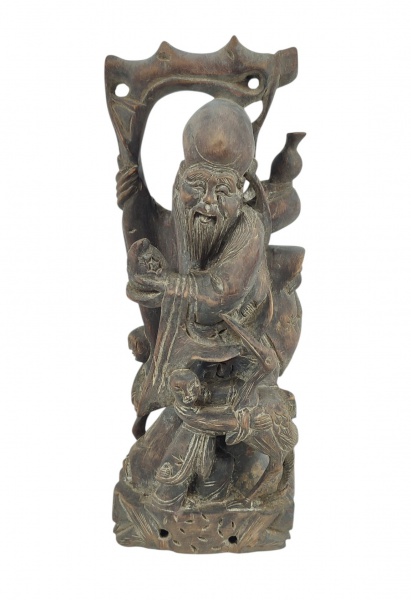Grupo escultórico em madeira entalhada, representando "Deus da Longevidade Shou Lao", adornado por crianças e uma ave. Apresenta desgastes causados pelo tempo. Alt. 30cm.