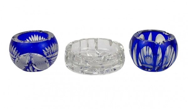 Três cinzeiros em cristal europeu, sendo dois na tonalidade double azul e translúcido e o outro translúcido, lapidados. Diâmts. maior e menor 14cm e 10,5cm.