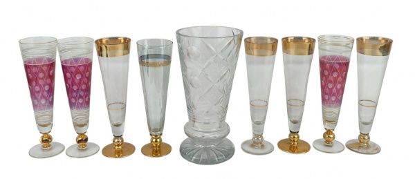 Nove peças, sendo vaso em cristal, lapidado em sulcos, bolas e rosetas e 8 tulipas em vidro, de diversos modelos e decorações. O vaso com bicado na borda e na base e as tulipas com desgastes nas decorações. Alts. 25,5cm. e 23,5cm.