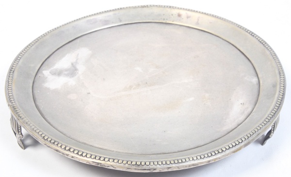 PRATA DE LEI - Bandeja circular em prata de lei, com medalhão central e pés ornamentados. Apresenta marcas de uso e desgaste, conforme fotos. Peso 812 g. Diâmetro 30,5 cm.