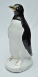 Estatueta em porcelana nas cores branca e preta, com detalhes à folha de ouro, representando "Pinguim de Geladeira". Med.: 25 cm.