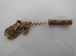 Sacarrolha na forma de arma em metal dourado adornado com pedrarias.