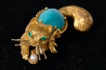 Delicado broche em ouro 18 k, retratando gato. Tendo em seu corpo, uma pedra original de turquesa, e seus olhos, duas esmeraldas. Designer desconhecido.
