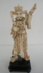 Figura masculina com dragão e a pérola flamejante. Escultura de osso policromado, sobre base em bois de fer. 48 cm de altura. China, séc. XX.