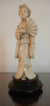 Escultura de marfim oriental representando gueixa com seus leques. Base em bois de fer. Med. 13 c alt. China, séc. XIX.