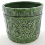 Cachepot em Formato de Barril em Cerâmica Vitrificada Verde, com detalhes de Flores em Alto Relevo. Medidas em cm. Diam X Alt - 12 x 13 cm,