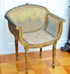 Poltona de padrão napoleônico, em madeira esculpida e  dourada. Assento e encosto de palhinha. Peça de época com pequenas falhas. Altura 79 cm.