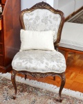 Bela cadeira Luiz XV de madeira esculpida com pátina dourada. Assento e encosto de tecido floral bege sobre fundo branco. Altura 93 cm. Largura 55 cm.