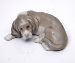 LLADRÓ - BEAGLE. Pequena estatueta de porcelana representando cachorro deitado. Marcado no fundo. Altura  2 x 6,5 cm.