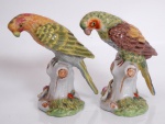Duas estatuetas europeias, de porcelana policromada representando pássaros pousados sobre troncos de árvores. Marca de manufatura. Alturas 9,5 cm.