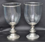 Dois castiçais para velas grossas, em vidro, base em metal. Altura 44,5 cm. Diâmetro 23 cm.