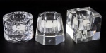 Três castiçais de cristal sueco (bloco maciço). Assinado: OLEG - CASSINI . Medida maior 7 cm. Medida menor 6,5 cm.