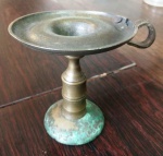 Pequeno castiçal em bronze, apresenta oxidação na base. Mede: 12 cm.