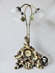 Belo abajur para 02 lâmpadas com base em resina Italiana. Possui relógio à quartz e rica decoração em forma de anjos e pássaros. Medidss de 69cm x 34cm x 17cm.