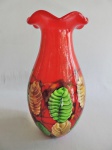 Murano - Belo vaso feito em pesado vidro de Murano na cor vermelha, com decoração em forma de folhas nos tons verde e bege com traços na cor preta. Medidas de 39cm x 18cm.