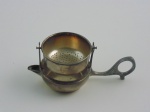 Coador de chá em metal prateado. Altura 5 cm.