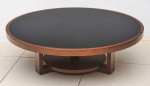 Elegante mesa redonda de centro, designer arrojado,em pesada madeira de lei e tampo em vidro negro. feita  Med. 110 x 38 cm. Estimativa entre 350 e 450 Reais.