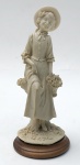 A. Belessi - Escultura italiana decorativa de material sintético com imagem de figura feminina com cesto de flores e base em madeira, aprox. 21 x 9,5 cm de diâmetro na base