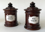 Par de potes com tampa de cerâmica vitrificada na tonalidade marrom `Fel Tauri e Flor Rosae` cada peça tem aprox. 15 x 10 cm de diâmetro 