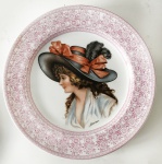 Prato decorativo de porcelana nacional creme, borda floral e desenho de figura feminina na parte interna, aprox. 19 cm de diâmetro 