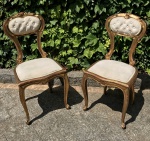 Par de cadeiras executadas em madeira ao estilo Luis XV, patinadas em dourado, assento e encosto revestidos em tecido na tonalidade bege, encosto com acabamento capitone, Aprox. 45 x 40 x 90 cm de altura