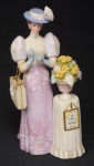 COLECIONISMO - Escultura em biscuit policromada representando " Dama em Viagem", entregue como um "Troféu Mrs. Albee - AVON 2006" inscrições na base. Med.: 25 cm.