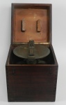 Bússola de bronze, caixa de madeira, da cabine do capitão. Caixa medindo 31 cm de altura x 27 de largura x 28 de profundidade, peça medindo 22 cm de diâmetro. (no estado)