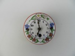 Pequeno relógio de parede com mostrador de porcelana decorada.
