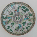 Prato em porcelana chinesa, famille vert, com pintura de cenas do cotidiano em oito reservas, centro e borda geométricas.Sec. XIX. diâmetro 21cm.