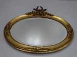 Espelho francês do séc. XIX, formato oval, de cristal bisotado, guardenecido com moldura de madeira entalhada e brunida a ouro, no estilo Luis XV. 80 x 65 cm altura.