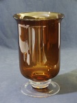 Vaso de vidro liso na tonalidade âmbar, base circular incolor. 23 cm diâmetro x 36 cm altura.