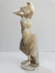 Escultura de mármore e alabastro na figura de jovem recostada com as mãos nos cabelos. 65 cm altura.
