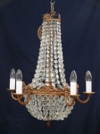 Gracioso lustre de bronze e cristal estilo império, para 10 luzes, decorado com laçarotes. Medindo aproximadamente 54 cm de diâmetro x 56 cm de altura.