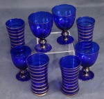 Conjunto de 4 copos e 4 taças de cristal azul decorados com frisos dourados.